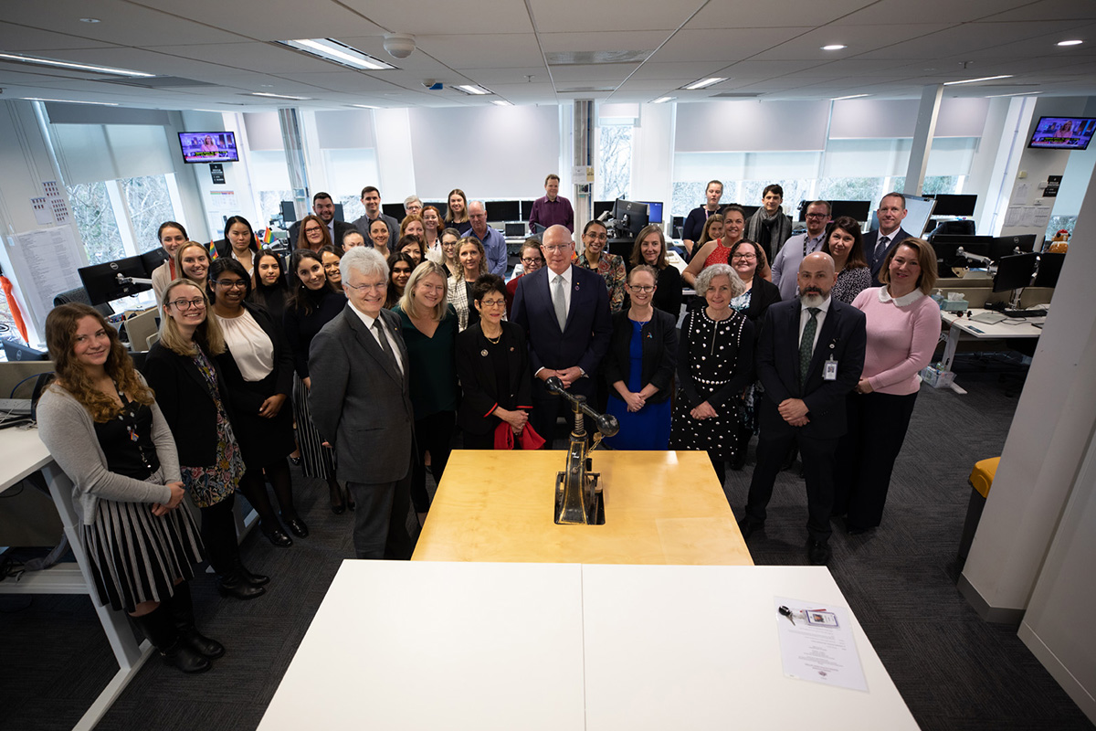 Professor Glyn Davis AC with approximately 40 PM&C staff surrounding former Governor-General Sir Peter Cosgrove in front of the Great Seal of Australia on a table. Professor Glyn Davis AC with approximately 40 PM&C staff surrounding former Governor-General Sir Peter Cosgrove in front of the Great Seal of Australia on a table.