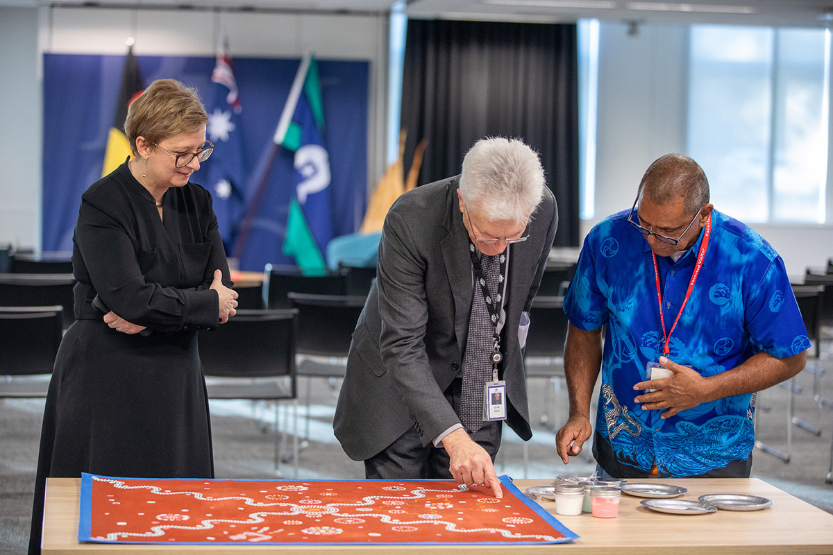 Professor Glyn Davis AC, James Baban, and another person looking down at James' artwork. Professor Glyn Davis AC, James Baban, and another person looking down at James' artwork.