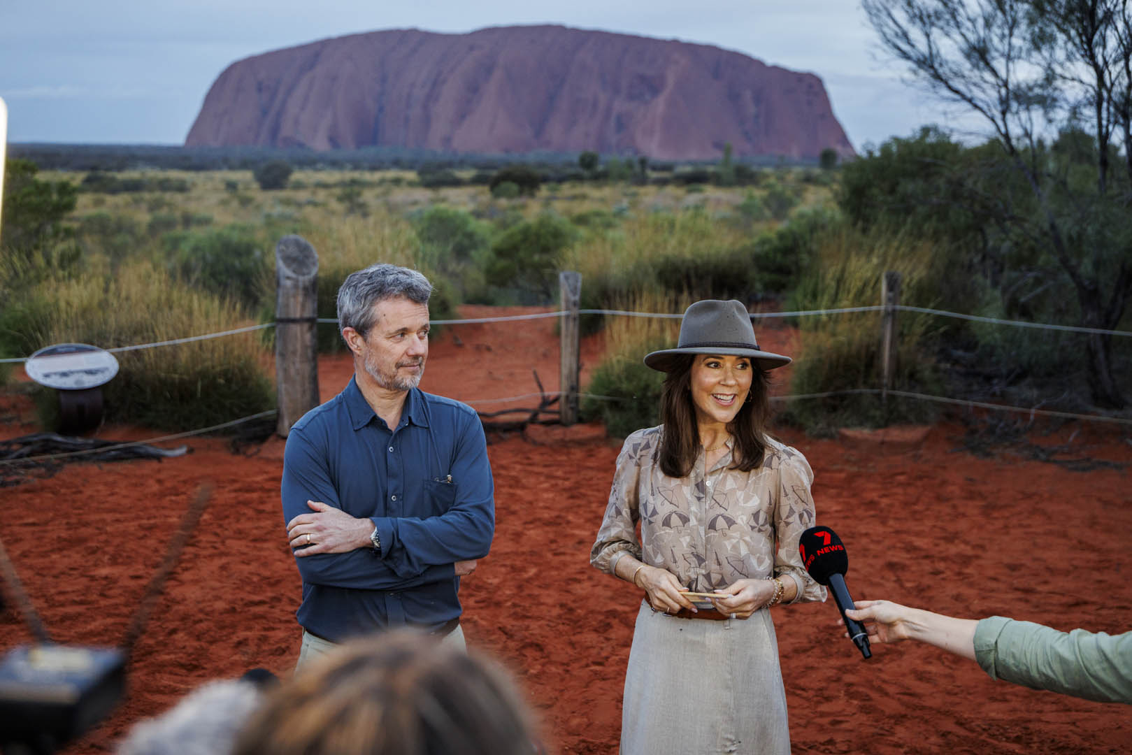 Their Majesties The King and Queen of Denmark being interviewed with a '7 NEWS' mic. Uluru rock formation visible in the background.