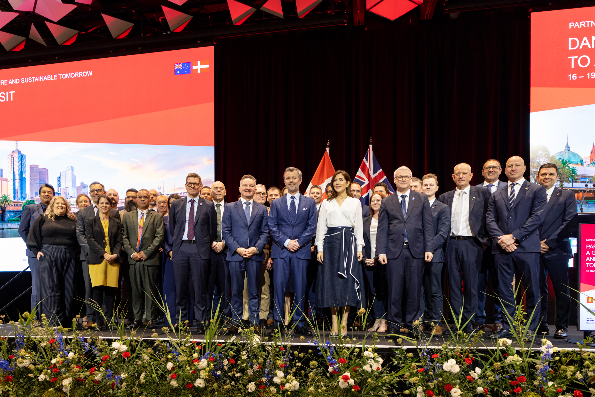 Group photo of dignitaries, including Crown Prince Frederik and Crown Princess Mary of Denmark, at "text@1". Australian and Danish flags are visible. "text@2" reads: 'PARTNERSHIP FOR A GREEN AND SUSTAINABLE TOMORROW, 16-19 MARCH'.