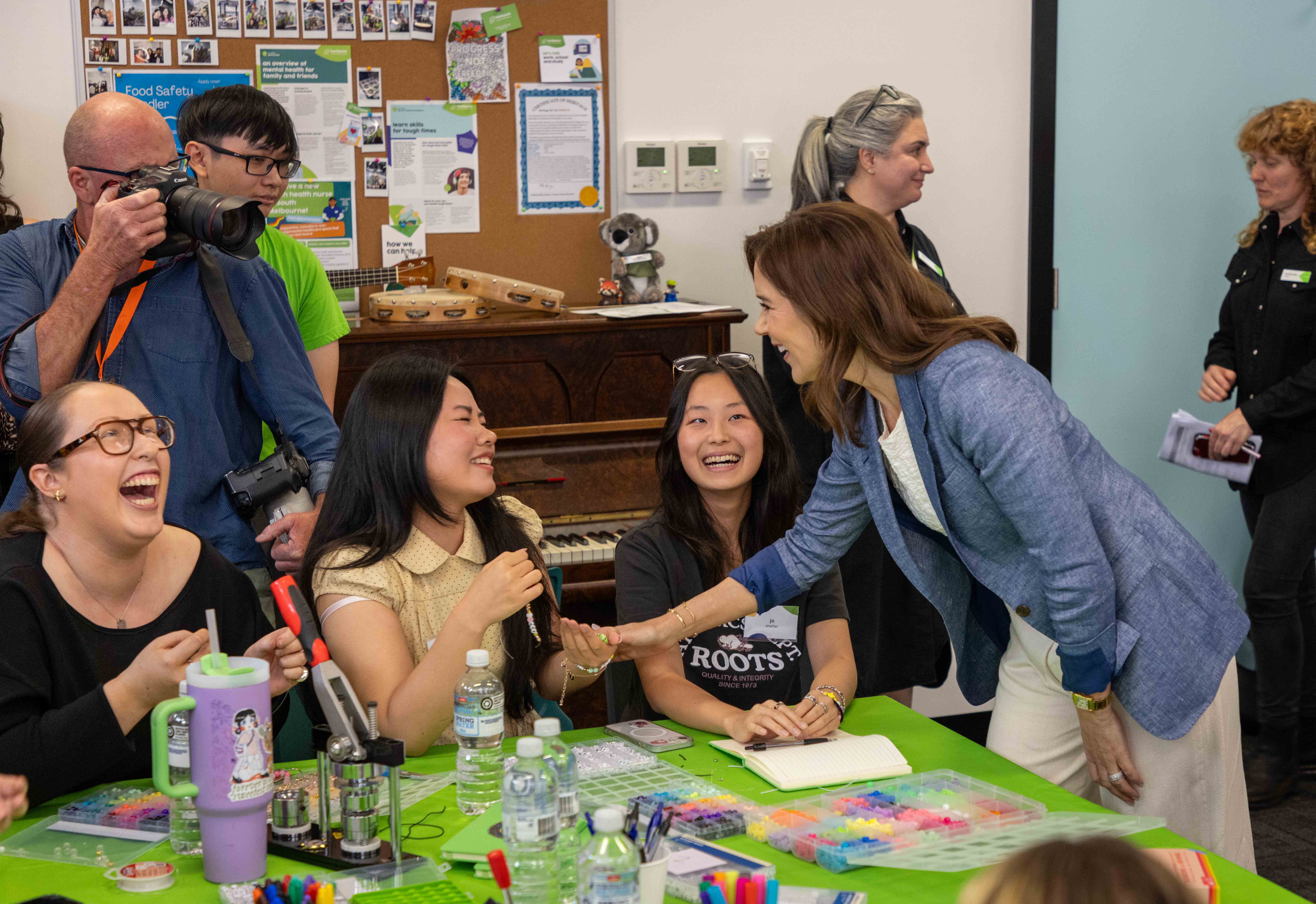 A group of about 30 people, diverse in race and gender, smile at the camera with His Majesty The King of Denmark in front of a screen with the text "headspace." Some hold name tags. Posters read "make space." 