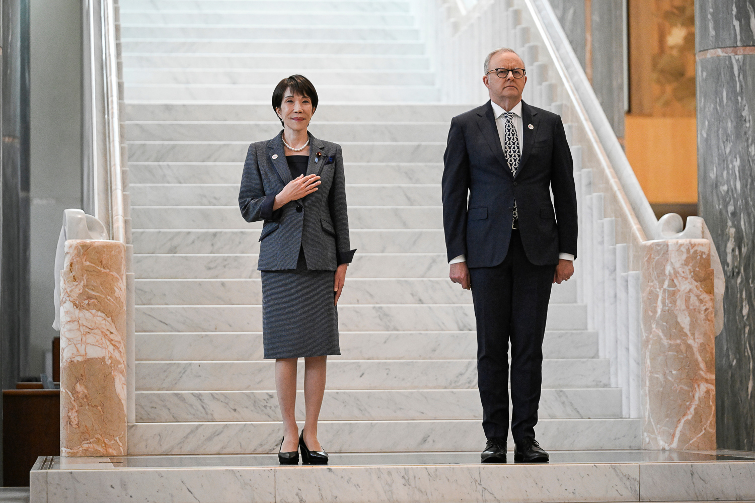 Prime Minister Anthony Albanese and Prime Minister of Japan Sanae Takaichi stand together at the base of a staircase during an official ceremony.