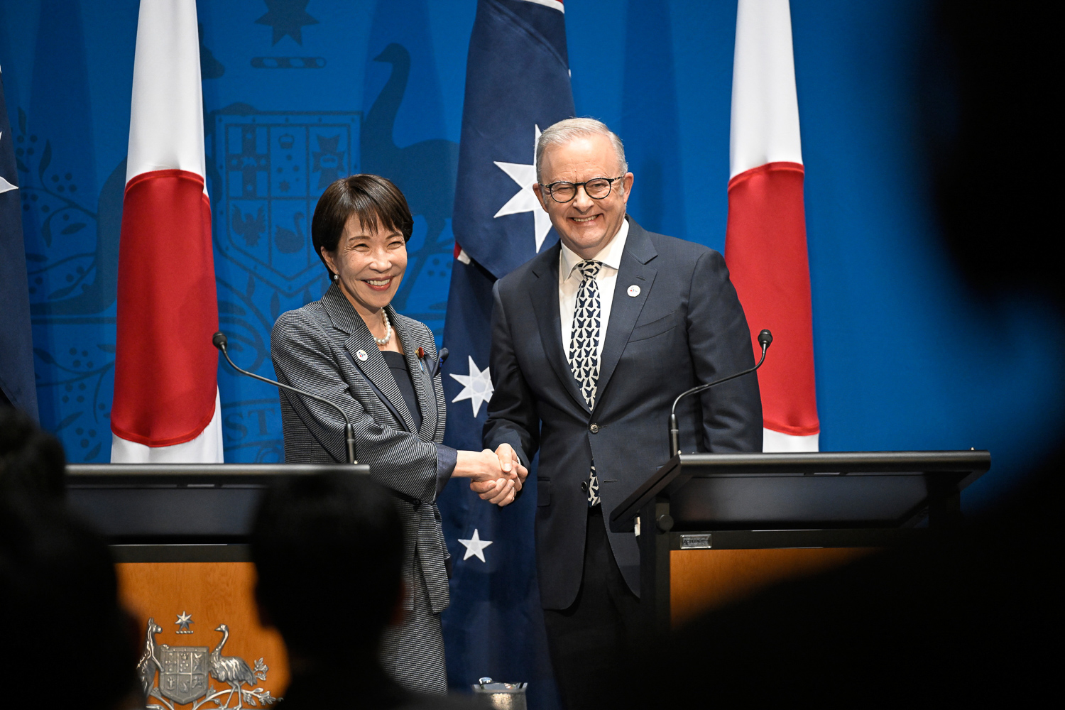 Prime Minister Anthony Albanese and Prime Minister of Japan Sanae Takaichi shake hands at a joint press conference podium.