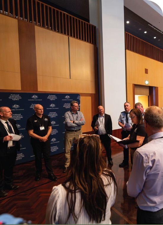 Senior leaders in uniforms and business attire at the National Preparedness Summit, standing in a circle for discussion