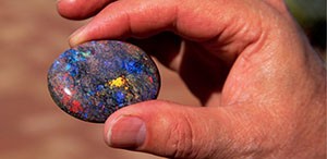Someone's hand holding a black opal.