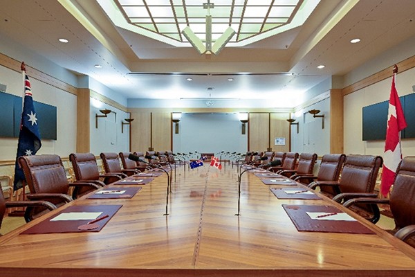 Conference table with desk flags and a large flagpole with a national flag on each side.