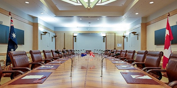 Conference table with desk flags and a large flagpole with a national flag on each side.