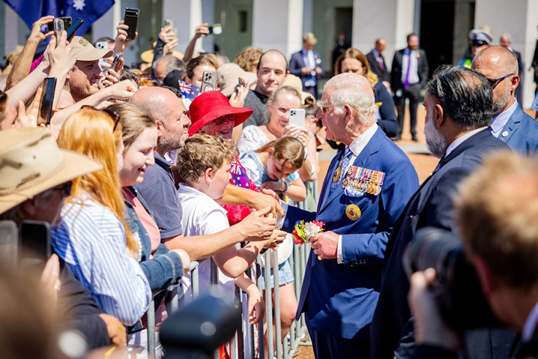 His Majesty greets a throng of cheerful well-wishers on the other side of a small barricade.