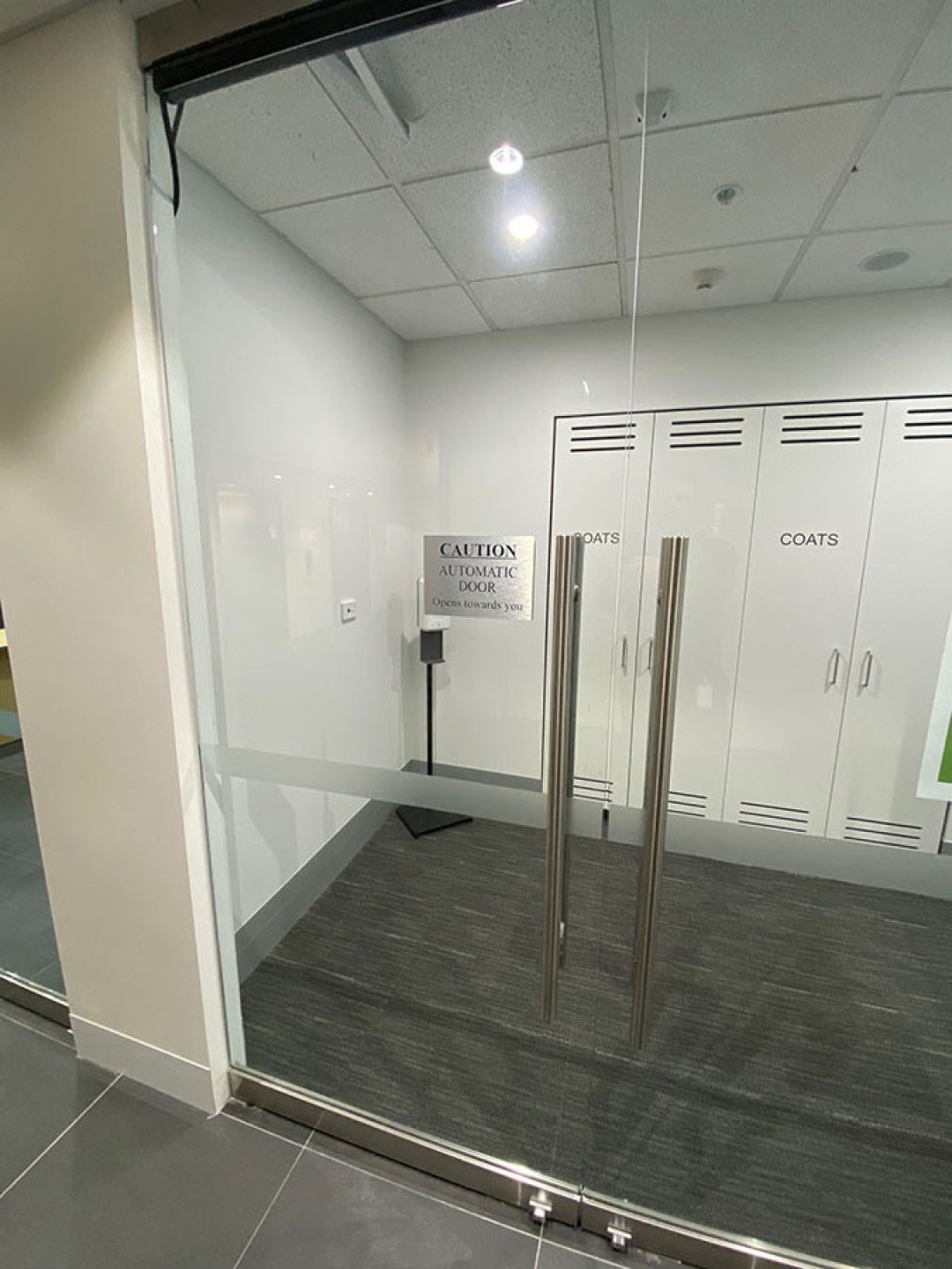 Shows glass sliding doors at 10 National Circuit which are auto operated from 06:00 – 18:00 weekdays for accessible access to the lift lobby.
