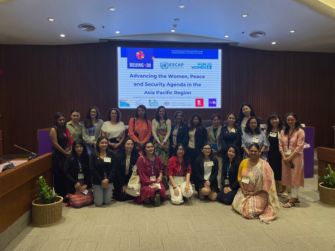 Australia’s Head of Delegation, Ms Padma Raman PSM, and Australia’s Ambassador for Gender Equality, Stephanie Copus Campbell, with a large group in front of a screen that says Advancing the Women, Peace and Security Agenda in the Asia Pacific Region.
