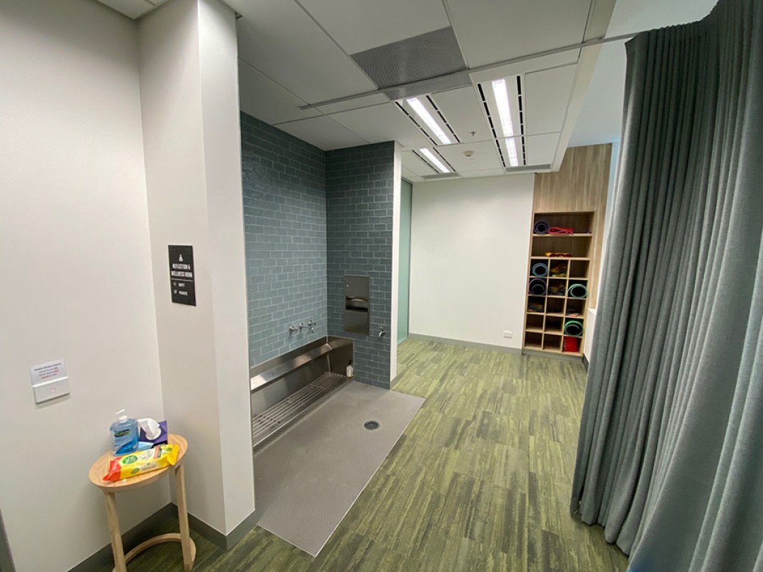 Shows a room with a foot wash sink, a privacy curtain and storage for prayer and yoga mats.