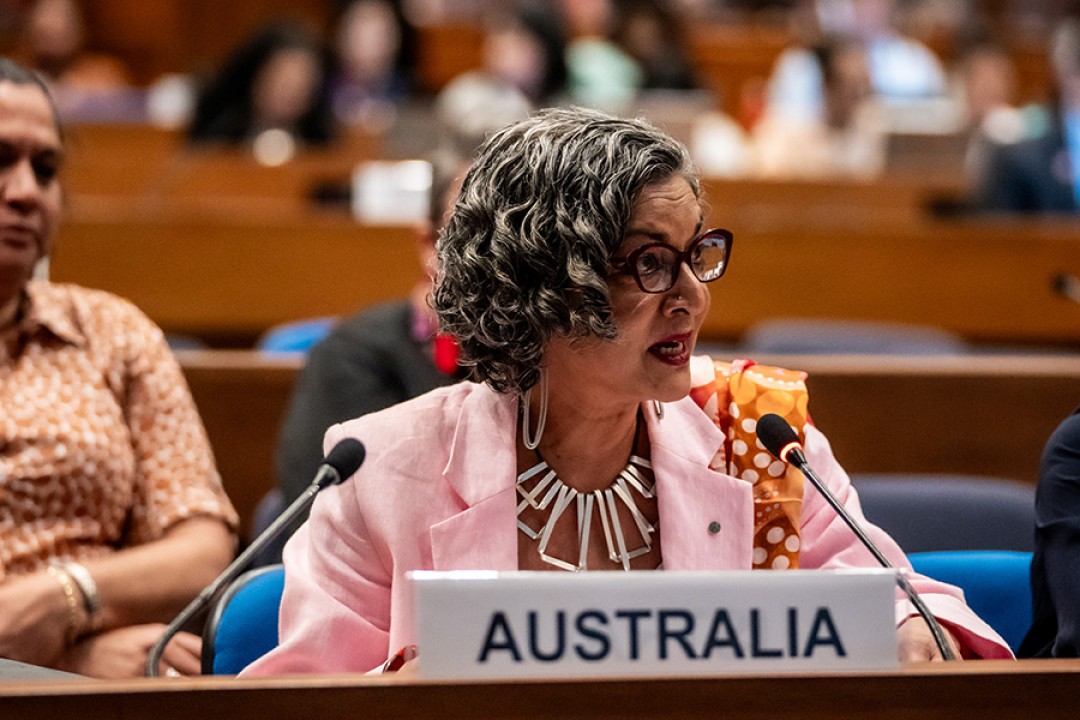 Australia’s Head of Delegation, Ms Padma Raman PSM, seated behind a microphone with a sign in front that says Australia.