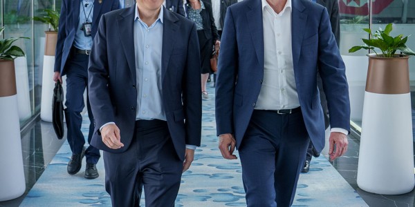 Prime Minister Anthony Albanese with Prime Minister Lawrence Wong in Singapore. They walk down a corridor followed by people.