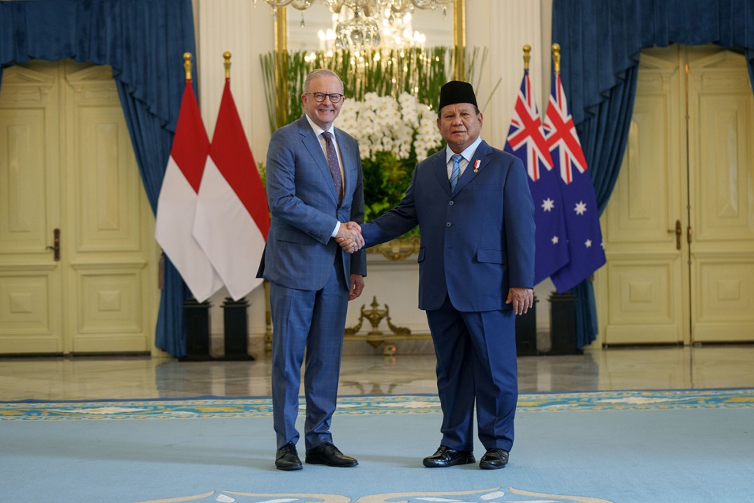 Prime Minister Anthony Albanese shakes hands with Indonesian President Prabowo Subianto in Jakarta in front of the flags of Indonesia and Australia.