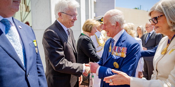 Professor Glyn Davis AC shaking hands with His Majesty King Charles III, while the Governor-General of Australia, Samantha Joy Mostyn AC, extends her hand to shake hands with another person. Other persons including Prime Minister Anthony Albanese are lined up to shake hands with people.