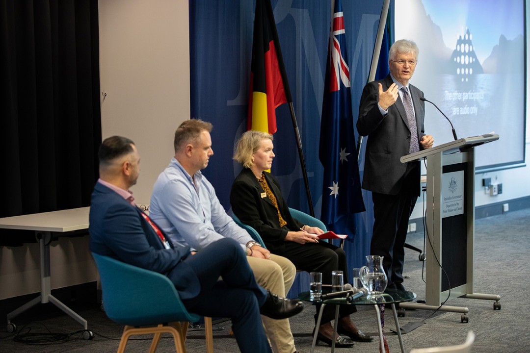 3 RUOK Day panel members seated next to Professor Glyn Davis AC speaking in front of a lectern.