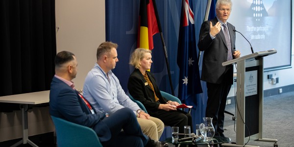 3 RUOK Day panel members seated next to Professor Glyn Davis AC speaking in front of a lectern.