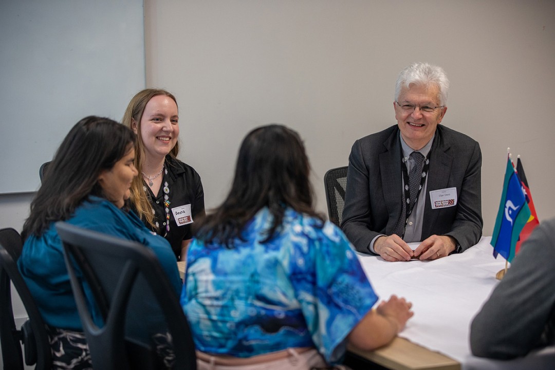 Professor Glyn Davis AC sits at a table with 3 other people.
