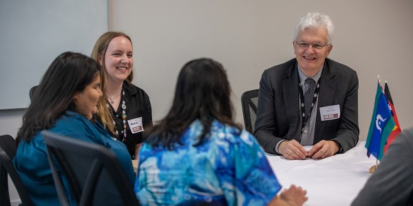 Professor Glyn Davis AC sits at a table with 3 other people.