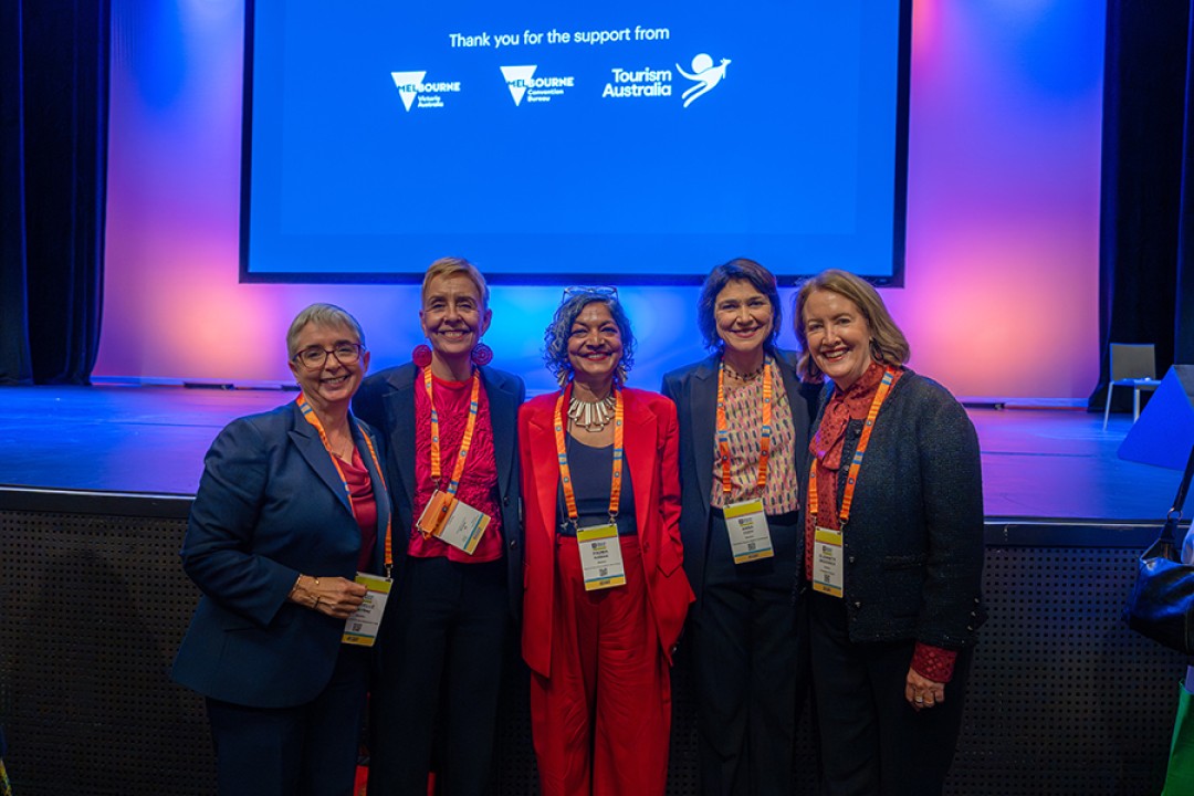 Michelle O’Byrne, Micaela Cronin, Padma Raman PSM, Anna Cody, Elizabeth Broderick AO standing in front of a stage with a blue and purple lit backdrop.