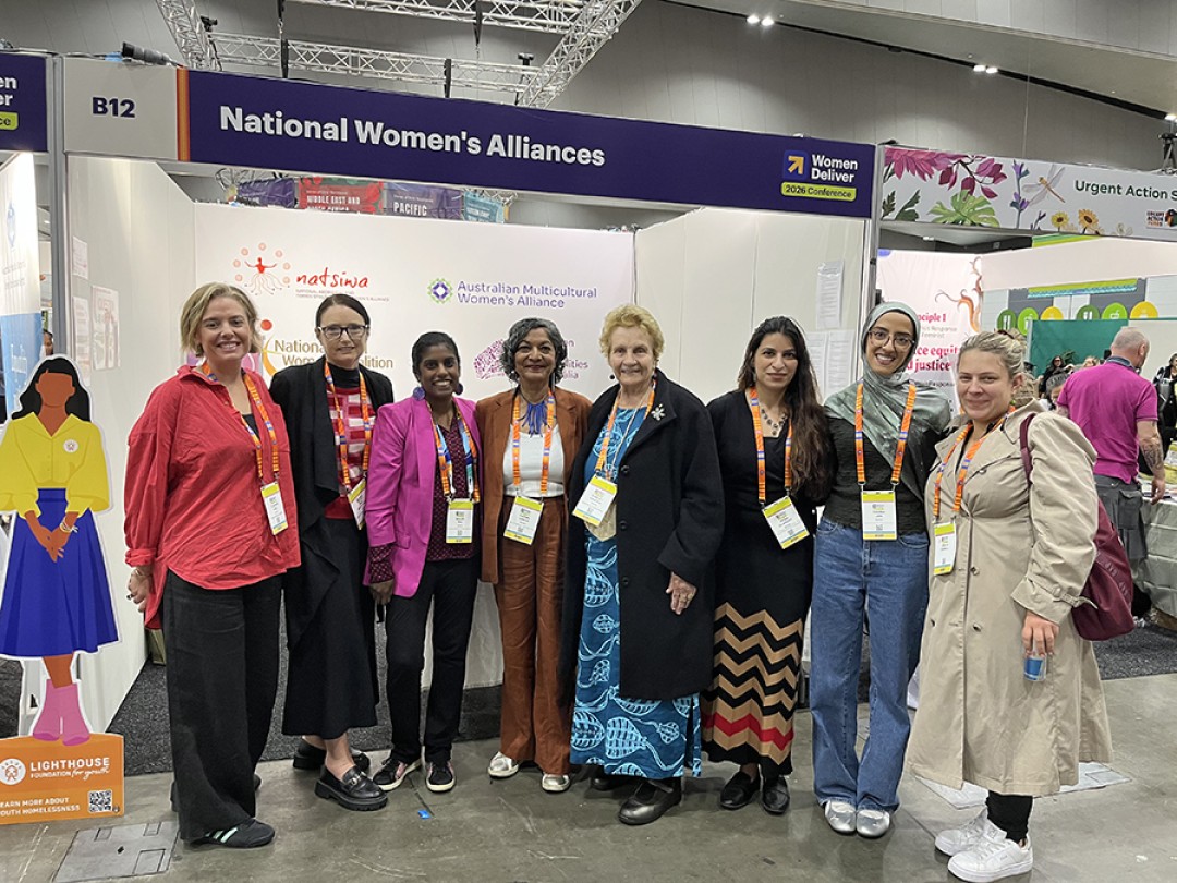 A photograph of Office for Women staff and National Women's Alliance members standing in a group in front of the National Women's Alliances booth.