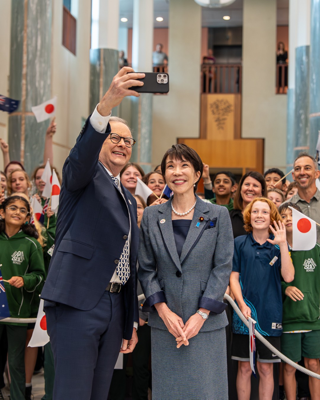 Prime Minister Anthony Albanese takes a selfie with Prime Minister of Japan Sanae Takaichi as crowds gather behind them.