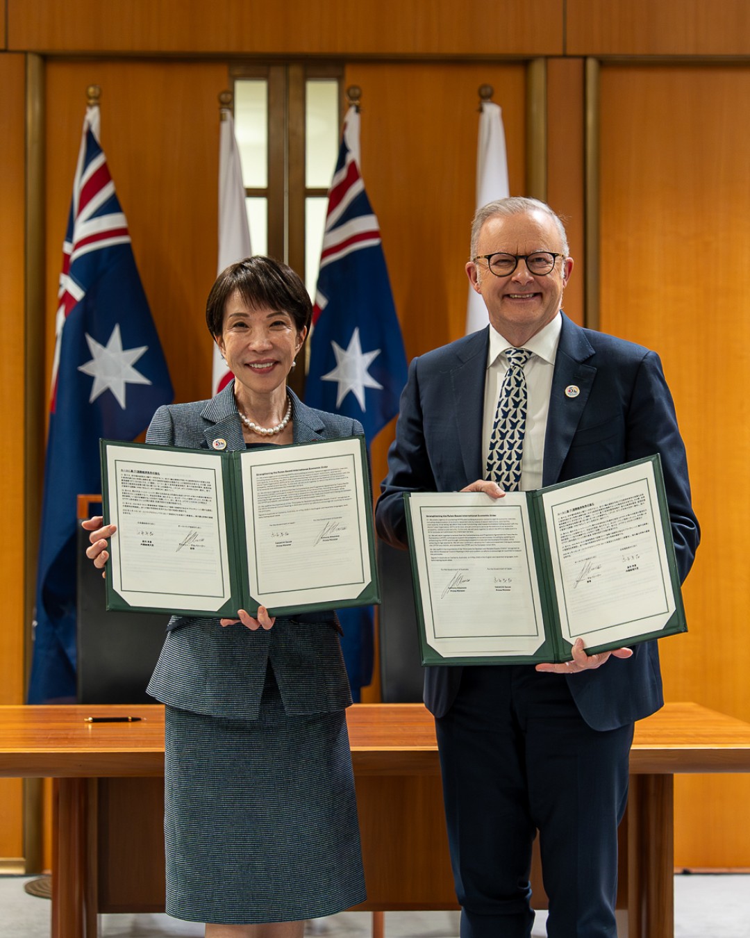 Prime Minister Anthony Albanese and Prime Minister of Japan Sanae Takaichi hold signed documents during a bilateral announcement.
