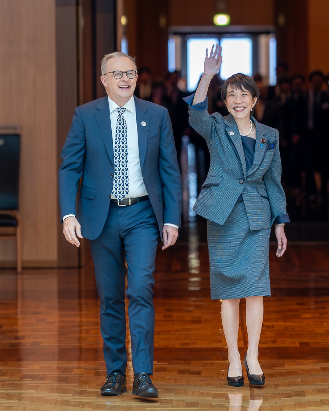 Prime Minister Anthony Albanese and Prime Minister of Japan Sanae Takaichi walk side-by-side through a formal building interior.