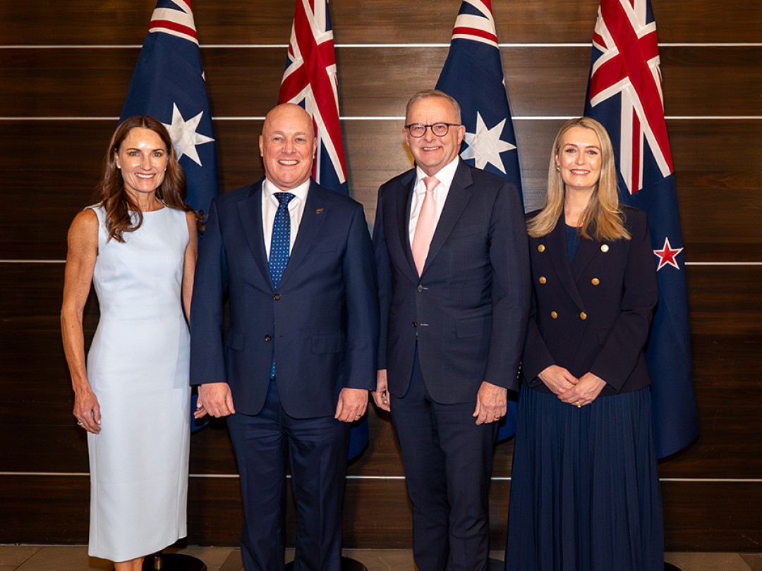 Prime Minister Anthony Albanese and New Zealand Prime Minister Christopher Luxon pose for a photograph with their partners in front of Australian and New Zealand flags.