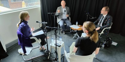 PM&C’s Lee Steel, Robin Edmonds and Andrew Pfeiffer are sitting in a circle with Work with Purpose podcast host, David Pembroke. They are sitting comfortably in a room while recording the podcast. A large window to the left is pouring sunlight into the room. 